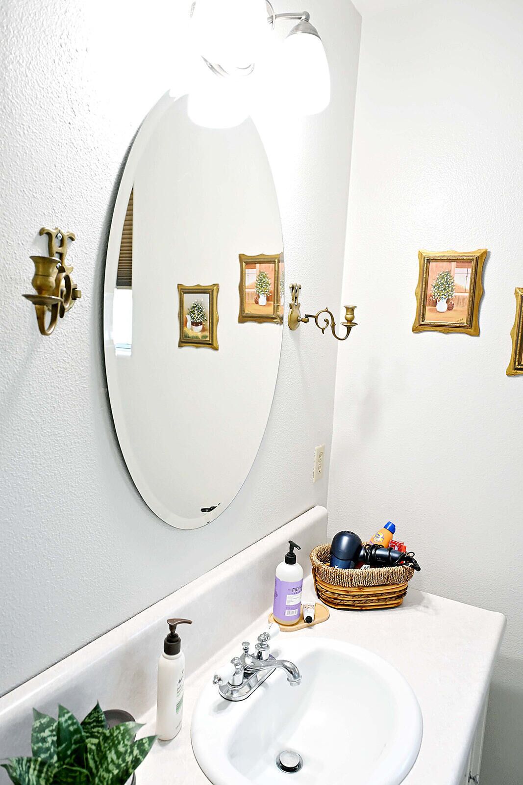 A bathroom with a white sink, a mirror, and a wall-mounted light fixture.