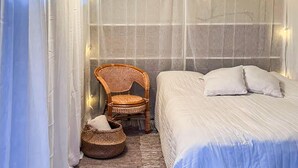 Una habitació amb un llit, una cadira i una cistella.