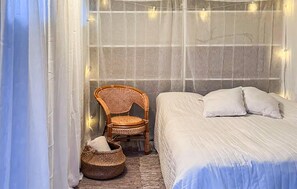 Una habitación con cama, una silla y una cesta.