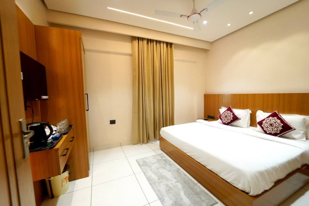 Habitación de hotel con cama, televisión, armario y cortina.