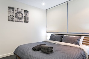 Ein Schlafzimmer mit Bett, Kissen, Kopfteil und Wandbildern.