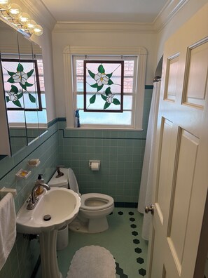 Ein Badezimmer mit Toilette, Waschbecken und einem Fenster mit floralem Glasbild.