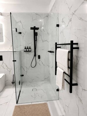 A modern bathroom with a glass-enclosed shower, marble walls, and a black towel rack. - Classic City Unit with Parking and walk to Harbour (Pyrmont)