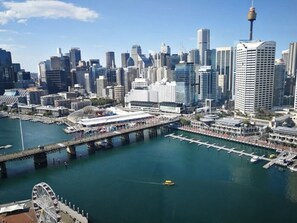 A waterfront cityscape with modern buildings, a prominent tower, and a pier with a Ferris wheel. - Classic City Unit with Parking and walk to Harbour (Pyrmont)