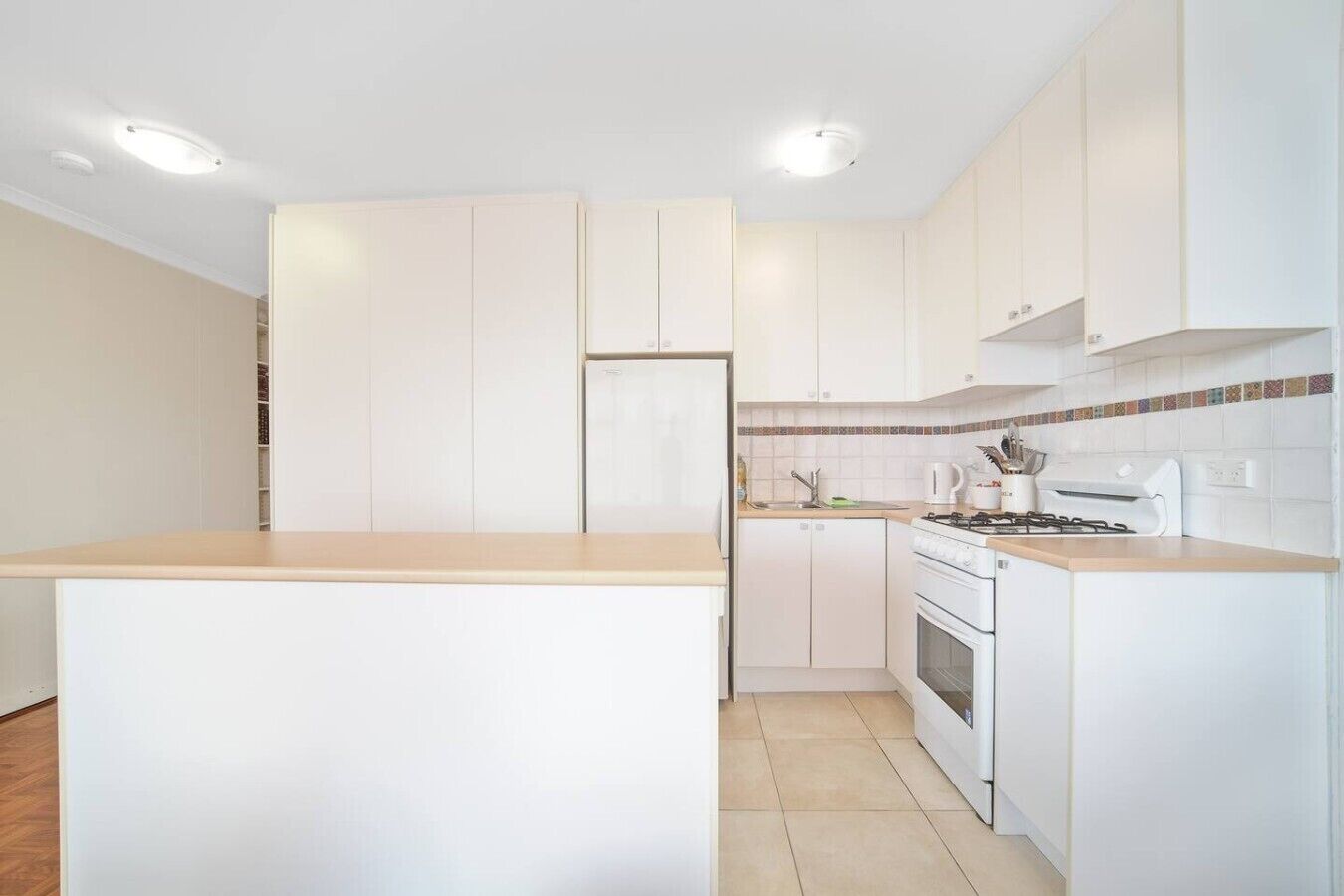 Una cocina moderna con armarios blancos, una isla central, una estufa y un lavamanos.