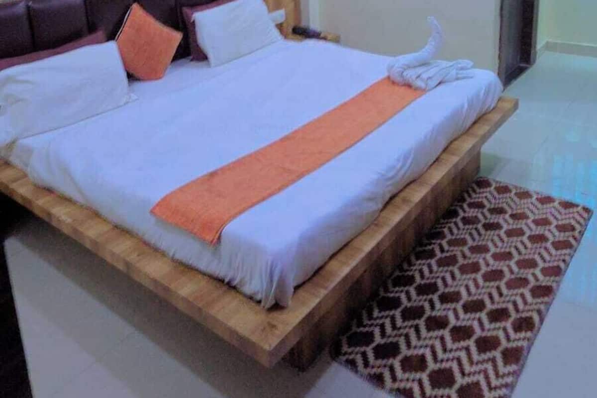 Ein Hotelzimmer mit einem großen Bett, einem Deckenventilator, einem gemusterten Vorhang und einem gefliesten Boden.