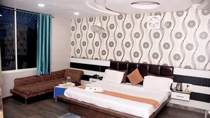 Habitación de hotel moderna con una cama grande, un sofá, una mesita de noche y una ventana con cortinas.