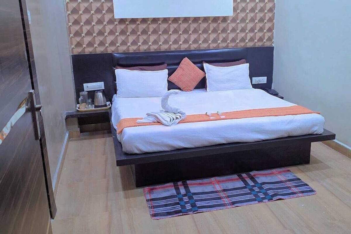 Ein modernes Hotelzimmer mit Bett, Nachttischen, einem Wand-TV und einem gemusterten Teppich.
