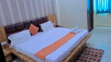 A hotel room with a bed, a ceiling fan, a patterned wall, and a window with curtains.