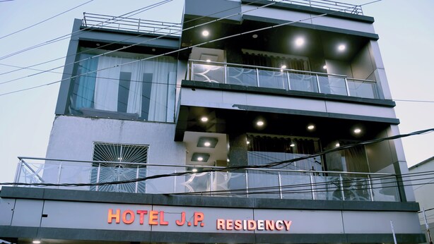 Un edificio de varios pisos con un letrero que dice 'HOTEL J.P. RESIDENCY'.