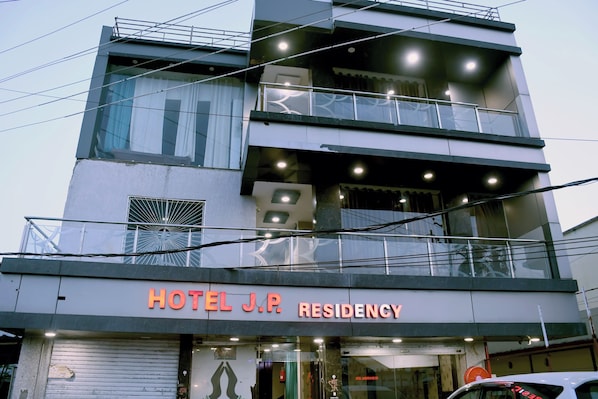 Un edificio de varios pisos con un letrero que dice 'HOTEL J.P. RESIDENCY'.