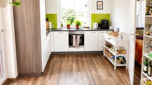 Una cucina moderna con mobili bianchi, pavimento in legno, una finestra con vista e un lampadario.