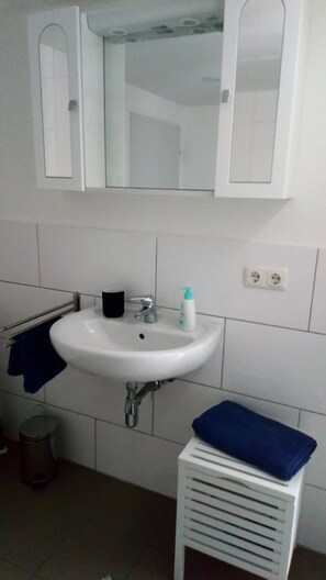 Une salle de bain avec un lavabo blanc, un miroir et un porte-serviettes.