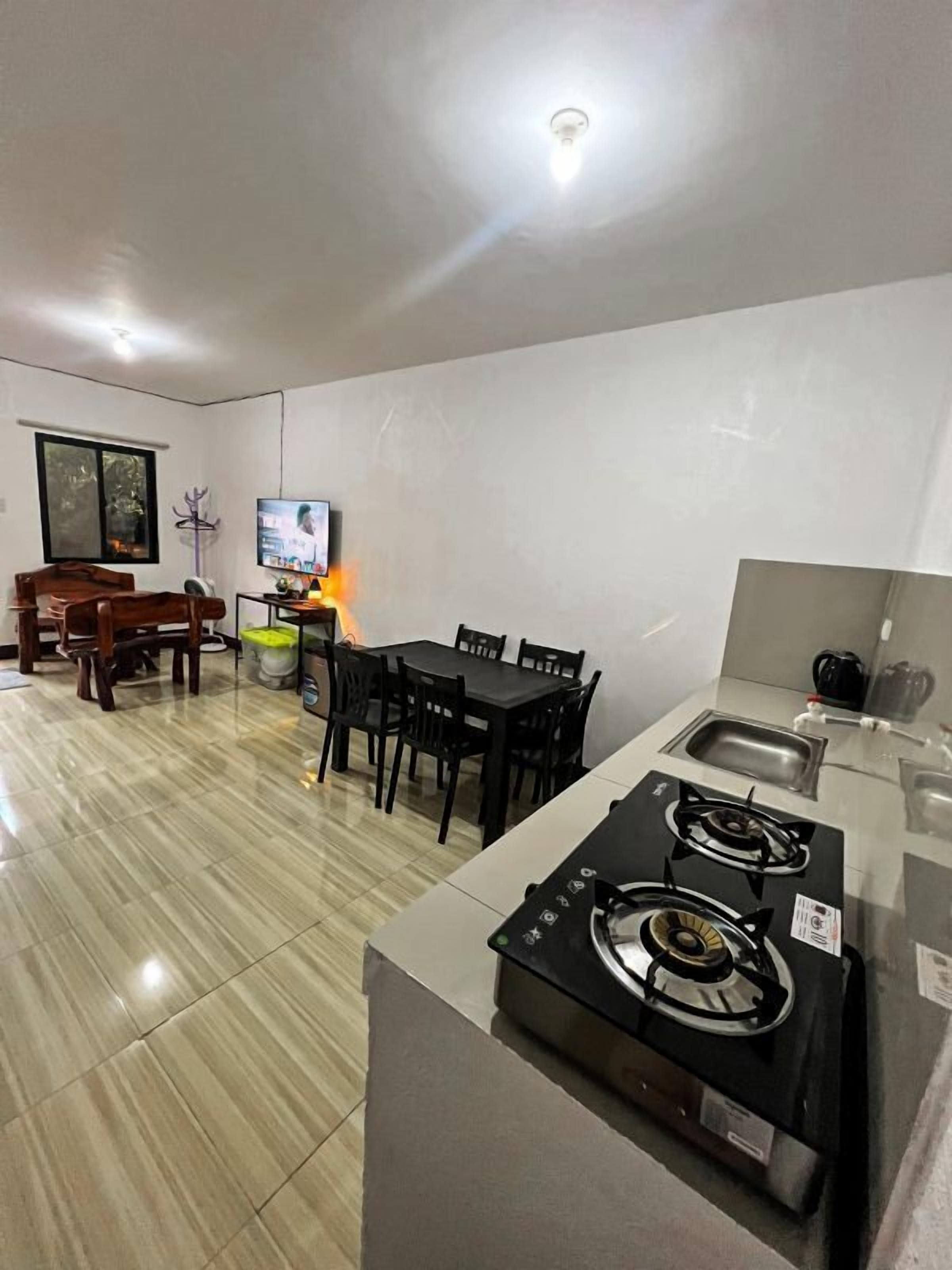 Cocina compacta con estufa a gas, comedor con mesa y sillas, y un televisor al fondo.