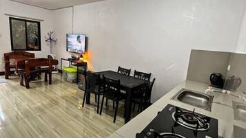 Cocina compacta con estufa a gas, comedor con mesa y sillas, y un televisor al fondo.