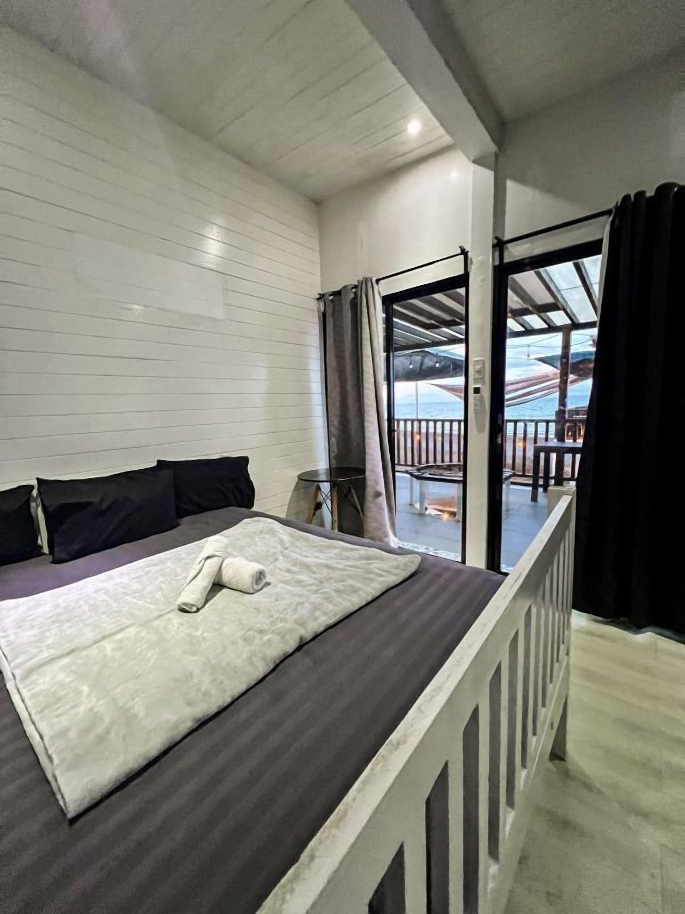 Habitación de hotel con cama, ventana con cortinas, vistas al exterior y un balcón.