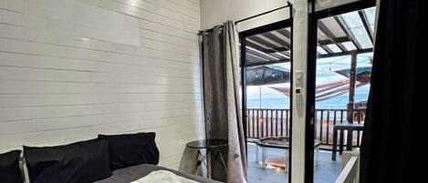Habitación de hotel con cama, ventana con cortinas, vistas al exterior y un balcón.