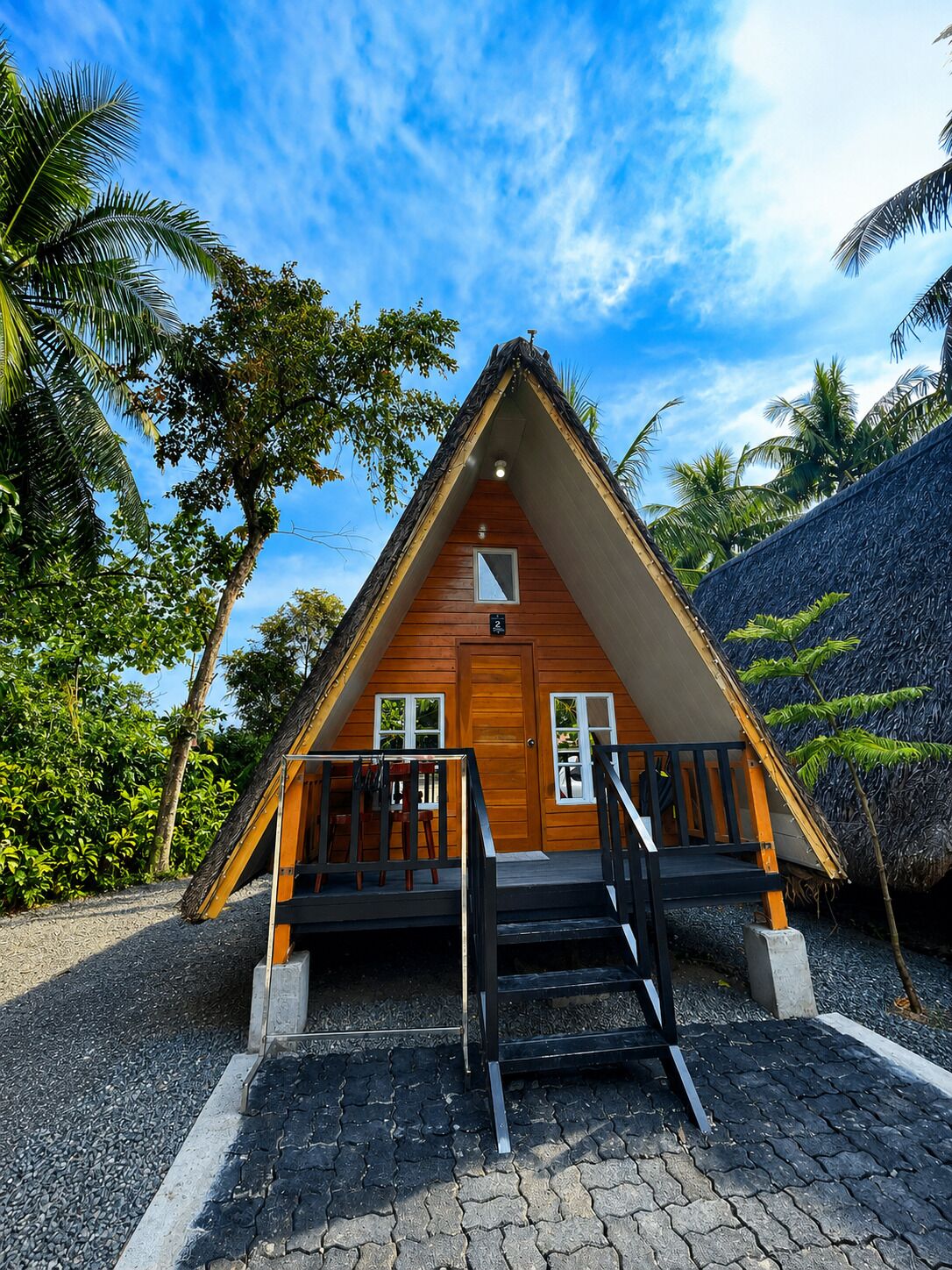 A triangular wooden cabin with a porch, a door, and two windows.