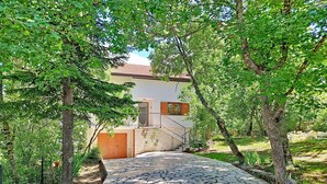 A stone pathway leading to a house with a brick wall and a wooden door, surrounded by trees. - Vacation home Orba by Interhome (Imotski)