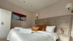 A neatly made bed with a quilted cover, a bedside table with a vase, and a painting on the wall. - Central Family Base in Antwerp (Antwerp)