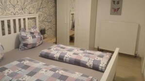 Une chambre à coucher avec un lit, une armoire, un radiateur et un mur décoré d’un motif.