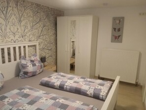 Un dormitorio con cama, armario, radiador y pared con diseño.