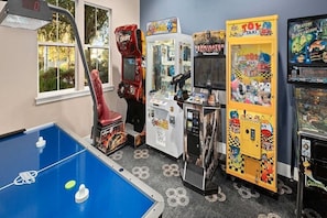 A room with a foosball table, claw machines, and arcade games.