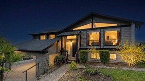 A modern two-story house with a visible staircase, a well-lit entrance, and a clear view of the interior through large windows. - Rainer Estate (Seattle)
