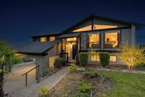 A modern two-story house with a visible staircase, a well-lit entrance, and a clear view of the interior through large windows. - Mins to Seattle~Lake Views~Movie Room/Game Room (Seattle)