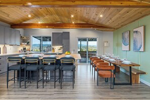 A spacious kitchen with a large island, modern bar stools, and a dining area with a long table set for a meal. - Mins to Seattle~Lake Views~Movie Room/Game Room (Seattle)