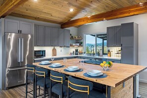 A modern kitchen with a wooden island, stainless steel appliances, and a view of the outdoors. - Mins to Seattle~Lake Views~Movie Room/Game Room (Seattle)