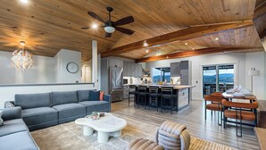 A modern living room with a gray sectional sofa, a white coffee table, and a ceiling fan. - Rainer Estate (Seattle)