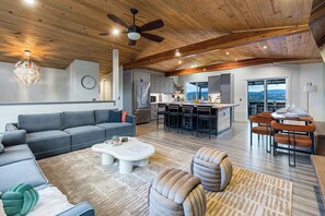 A modern living room with a gray sectional sofa, a white coffee table, and a ceiling fan. - Mins to Seattle~Lake Views~Movie Room/Game Room (Seattle)