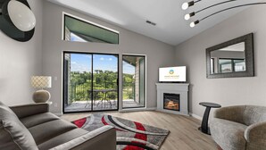 Un salon moderne doté d’une cheminée, d’un téléviseur et d’un balcon offrant une vue agréable.
