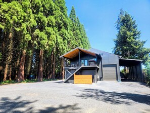 Una casa moderna con un garaje amplio, un porche cubierto y vistas a altos árboles.