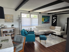 A modern living room with a white sofa, teal armchair, and a small round table.