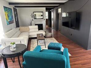 A modern living room with a sofa, teal armchairs, a coffee table, and a fireplace.