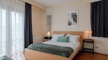 Een netjes ingerichte hotelkamer met een bed, nachtkastjes, een lamp en een raam met gordijnen.