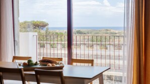 A dining area with a table and chairs, a view of the sea, and a balcony with a railing. - Casa Forno de Cal - By WeHostMadeira (Porto Santo)