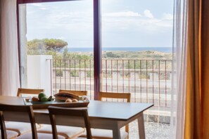 Ein Essbereich mit Tisch und Stühlen, Meerblick und ein Balkon mit Geländer.