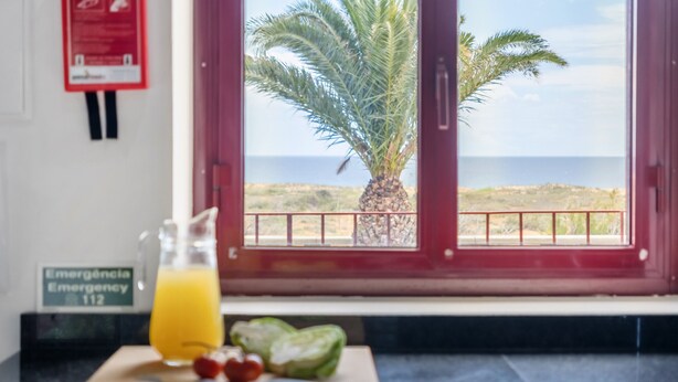 A kitchen counter with a cutting board, a knife, a bottle of orange juice, and a bowl of fruit. - Casa Forno de Cal - By WeHostMadeira (Porto Santo)