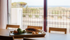 A dining table with a bowl of fruit and a papaya on a wooden tray, overlooking a balcony with a view of the sea. - Casa Forno de Cal - By WeHostMadeira (Porto Santo)