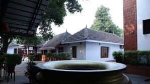 A traditional building with a tiled roof, a large decorative pot, and potted plants. - KABANI HERITAGE (Aluva)
