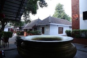 A traditional building with a tiled roof, a large decorative pot, and potted plants. - KABANI HERITAGE (Aluva)