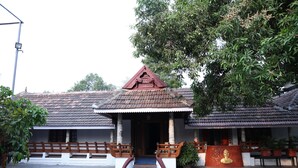 A traditional building with a tiled roof, a central staircase, and a small Buddha statue. - KABANI HERITAGE (Aluva)