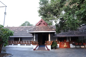 A traditional building with a tiled roof, a central staircase, and a small Buddha statue. - KABANI HERITAGE (Aluva)
