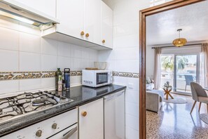 A kitchen with a gas stove, microwave, and white cabinets. - Appartement Don Pepe - Javea, Costa Blanca (Javea)