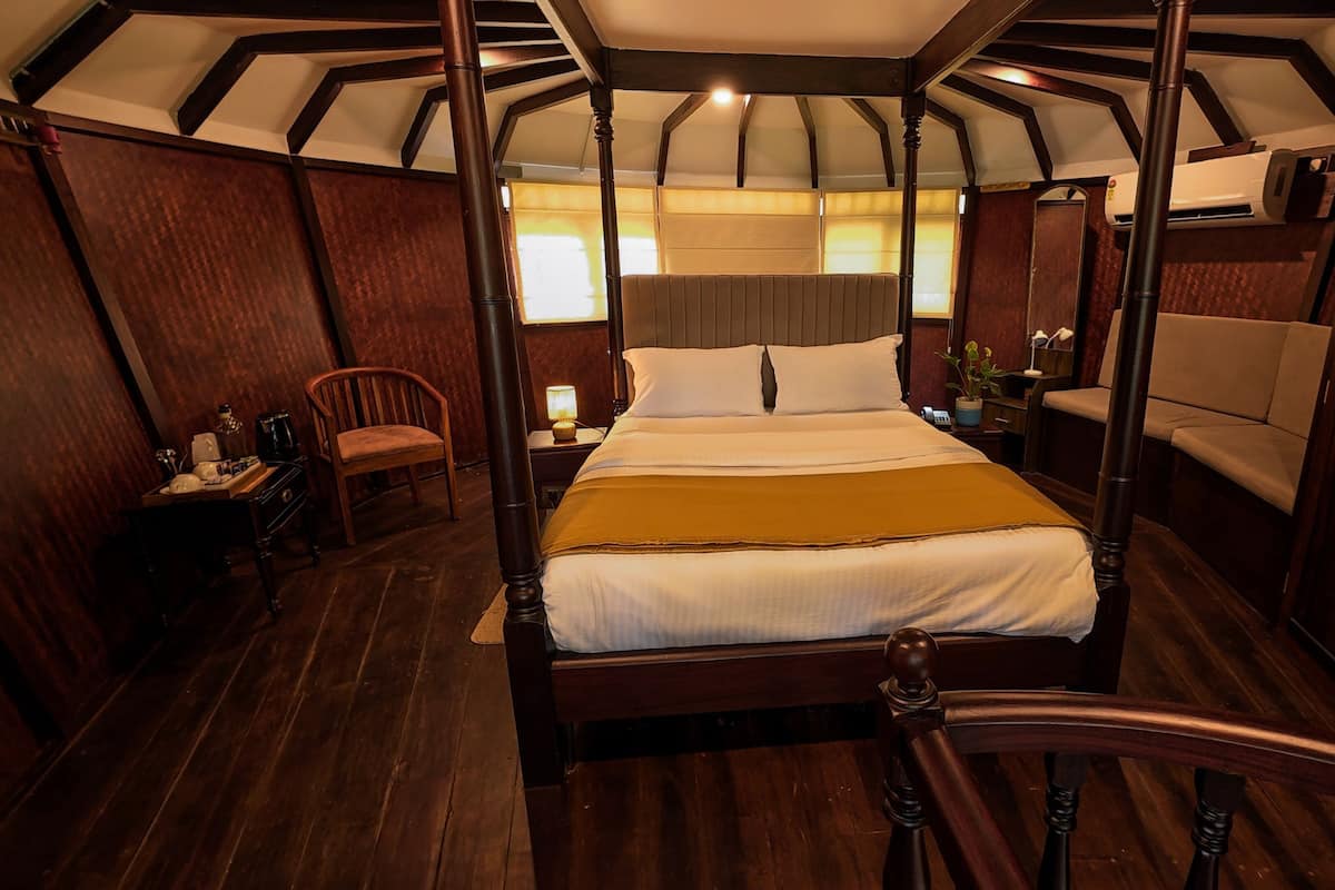 A four-poster bed in a room with wooden walls and a sloped ceiling.