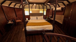 Una cama con dosel en una habitación con paredes de madera y techo inclinado.
