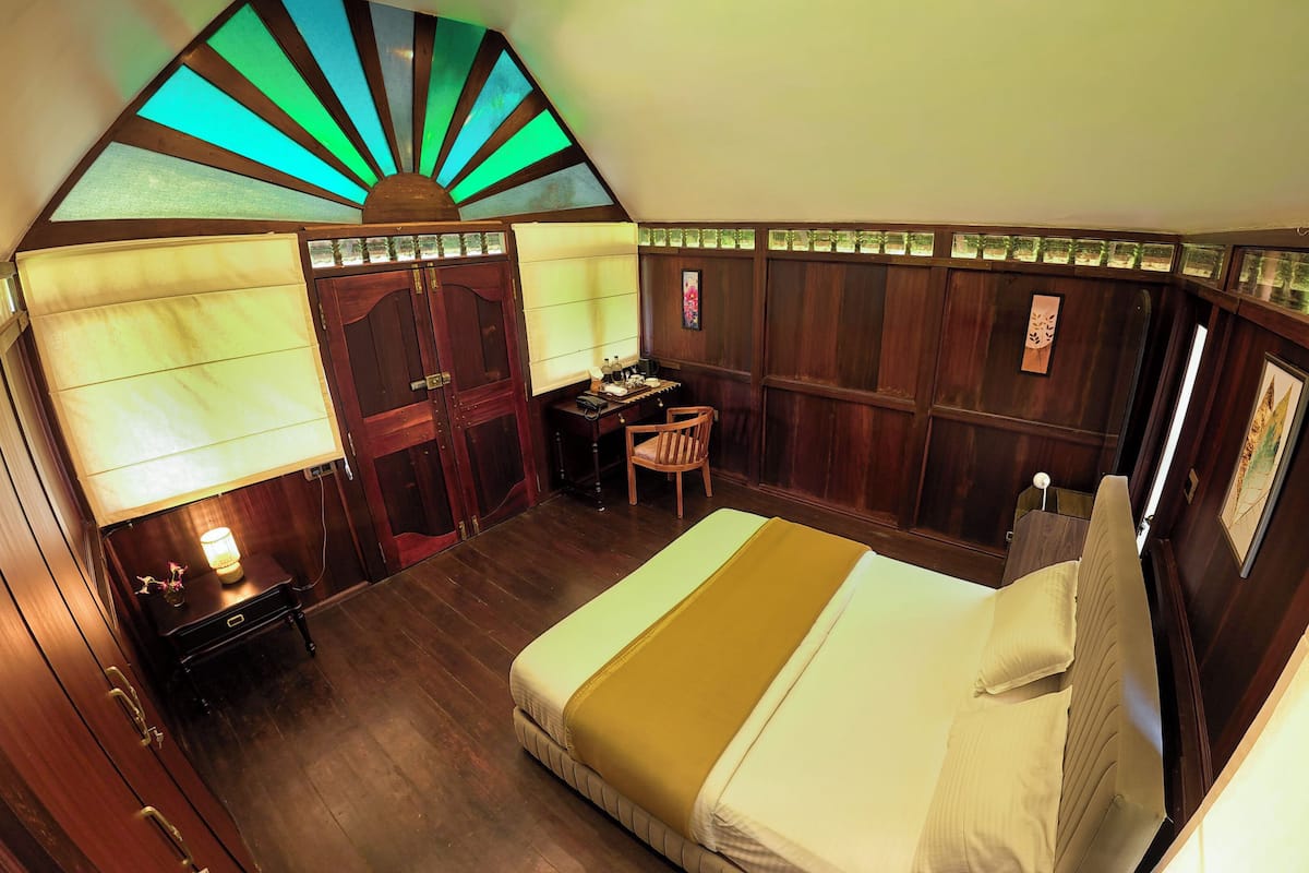 A room with a bed, a desk, a chair, and a large window with a view.